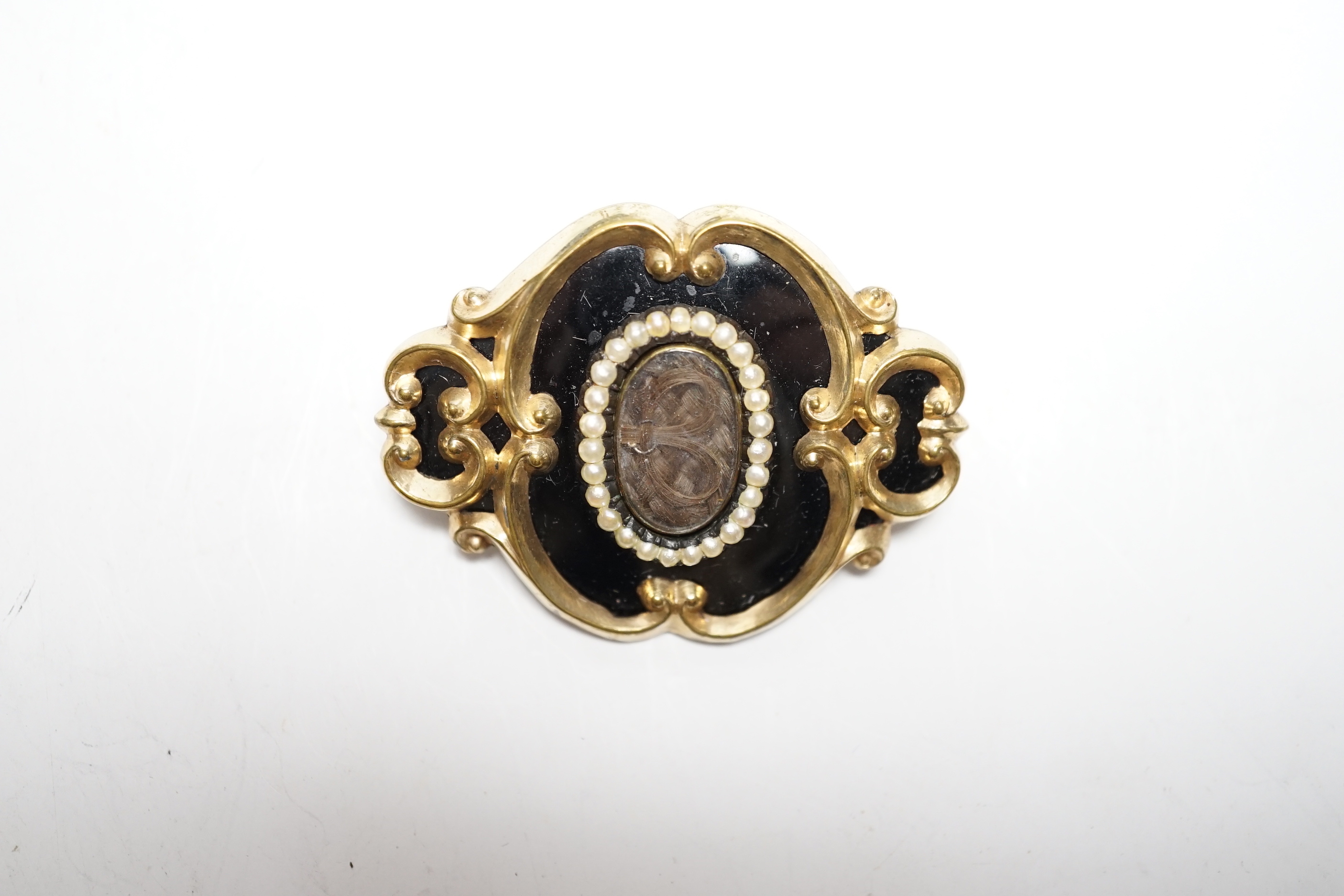 A Victorian yellow metal, black enamel and seed pearl set mourning brooch, 47mm.